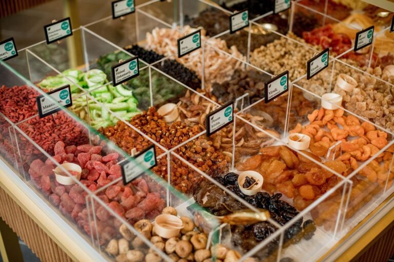 A vibrant selection of dried fruits in transparent containers at a market stall.