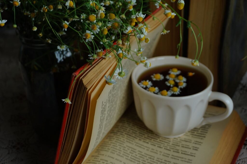 Calming scene with an open book, chamomile tea, and flowers.