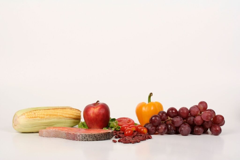 Vibrant display of fruits, vegetables, and salmon on a white background, ideal for food and health themes.