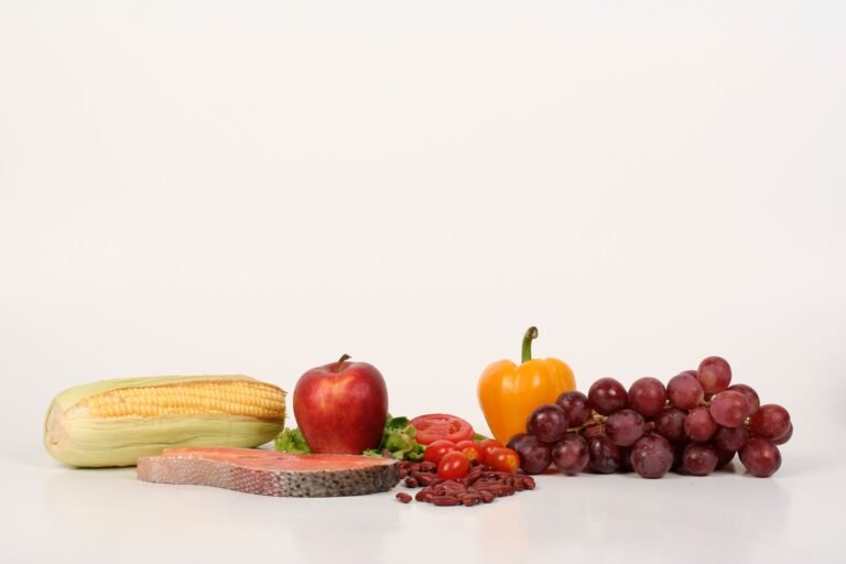 Vibrant display of fruits, vegetables, and salmon on a white background, ideal for food and health themes.