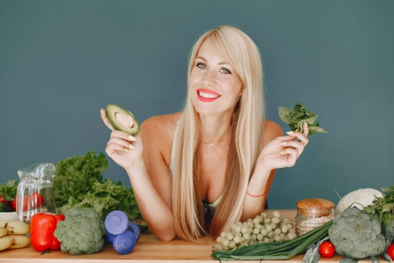 Blonde woman promotes healthy eating with fresh vegetables and fruits on display.