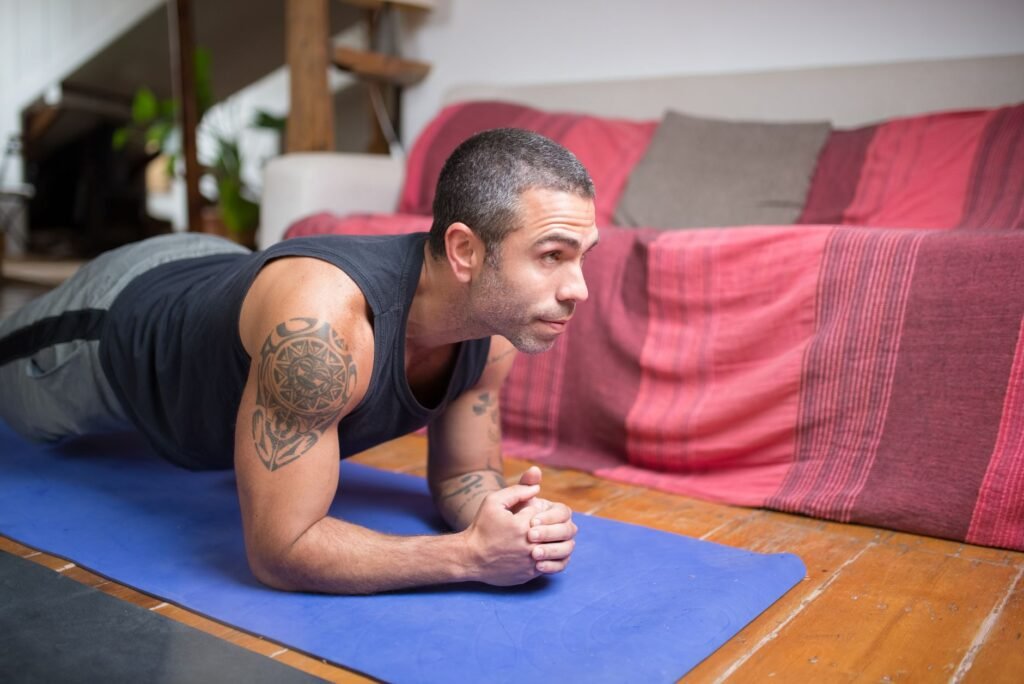 Man doing plank exercise indoors on a yoga mat, embracing a healthy lifestyle.