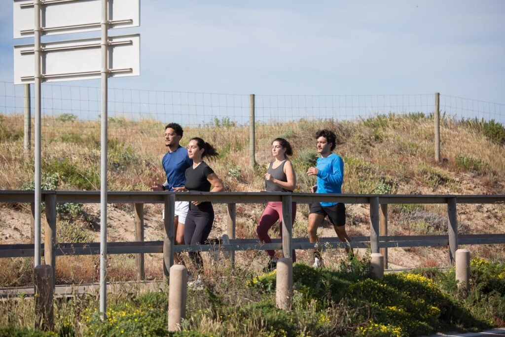 Four adults jogging on a boardwalk in Portugal, promoting a healthy lifestyle.