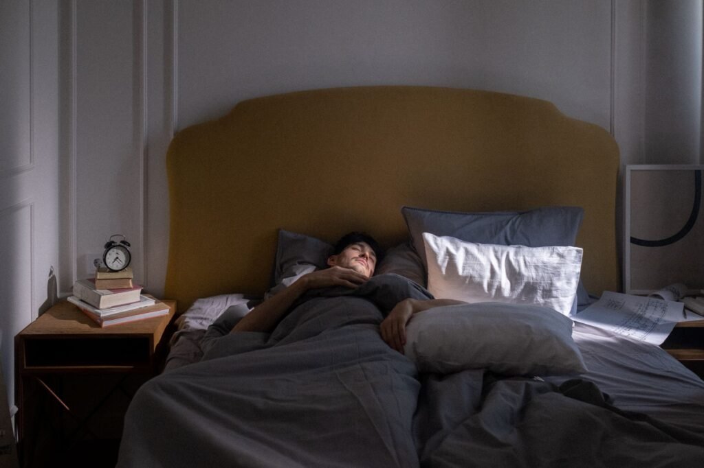 A man sleeping in a cozy bed with soft morning sunlight filtering in.