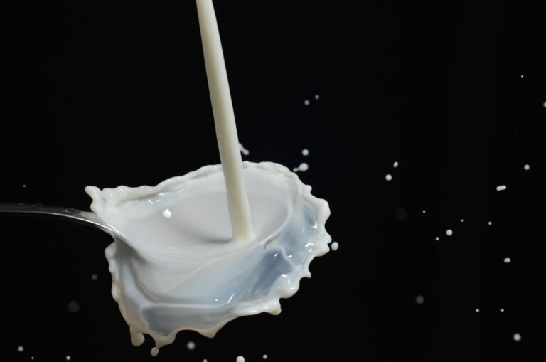 Capturing a dynamic splash of milk on a spoon in mid-air with dark background.