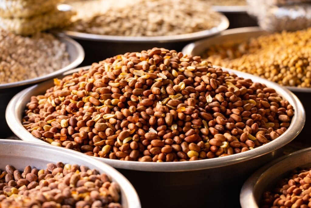 Close-up of roasted nuts in stainless bowls at a market, showcasing a variety of healthy and nutritious snacks.