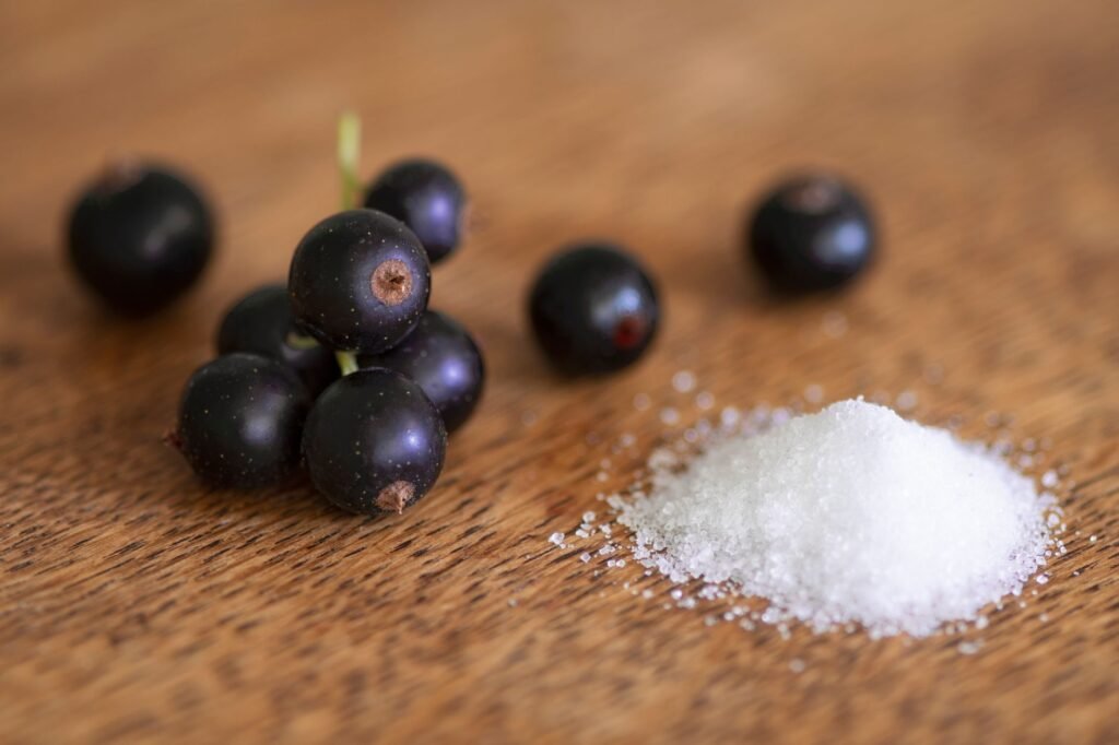 Close-up of fresh black currants and salt on a wooden surface, highlighting texture and contrast.