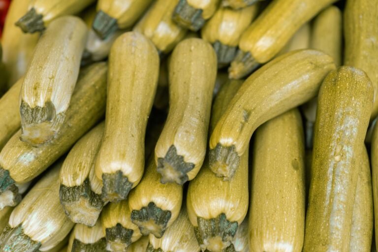 Close-up of fresh zucchinis at a market, showcasing their nutritious appeal and abundance.