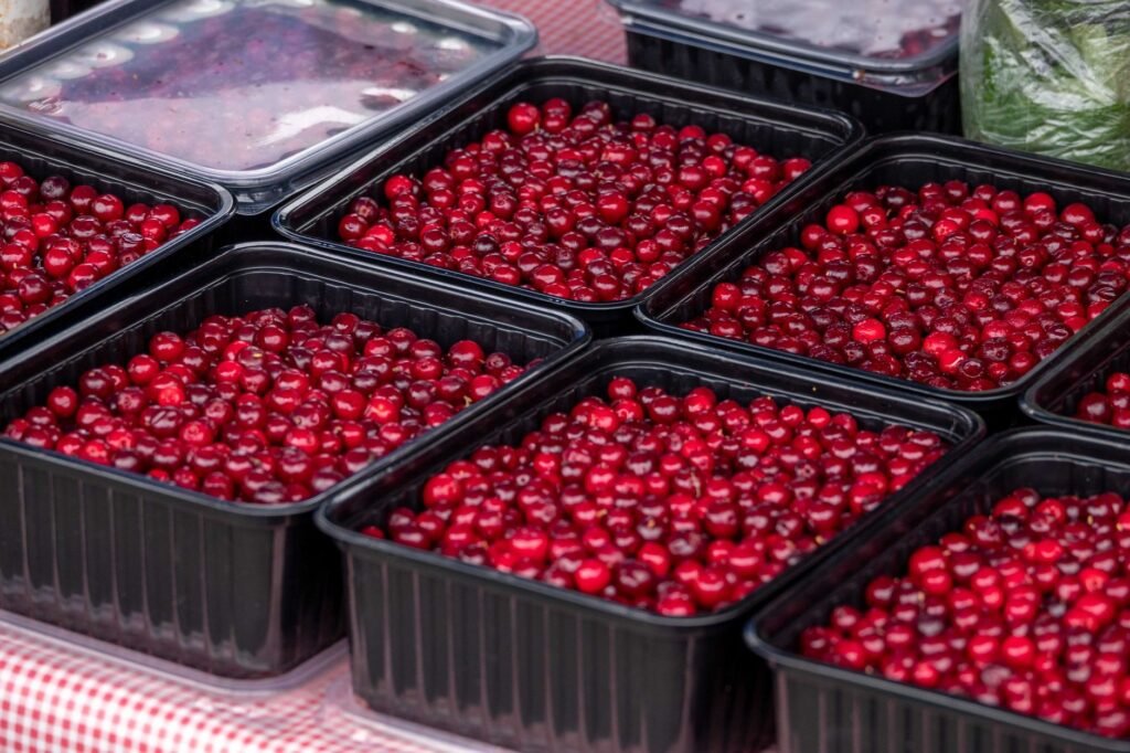 Close-up of fresh cranberries in black trays at a market.