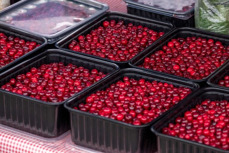Close-up of fresh cranberries in black trays at a market.
