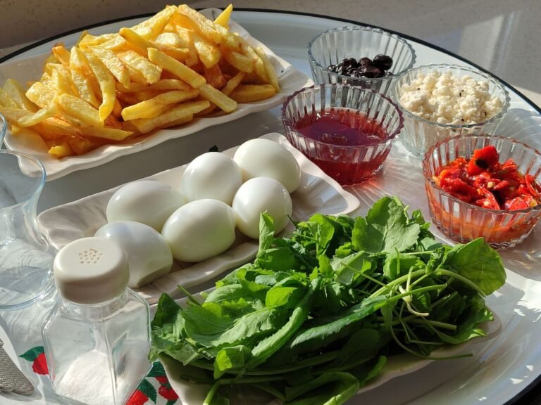 Colorful breakfast table with eggs, greens, fries, olives, and more, perfect for a balanced start.