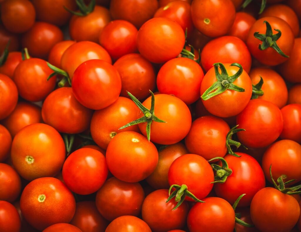 Close-up of fresh red cherry tomatoes with green stems, showcasing vibrant color and texture.