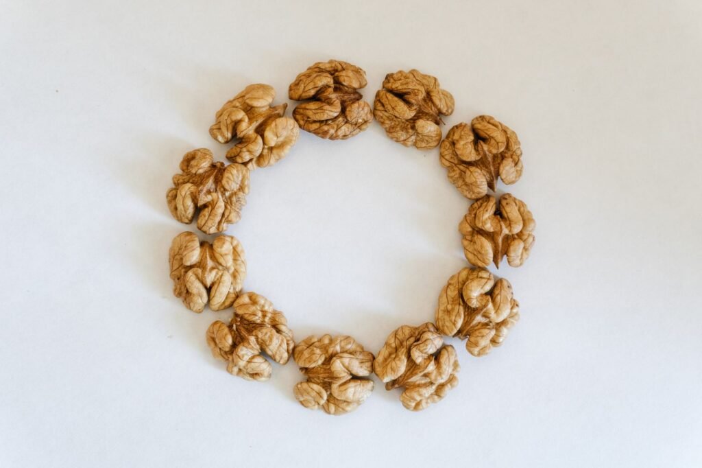 Top view of walnuts arranged in a circle on a white background, showcasing texture.