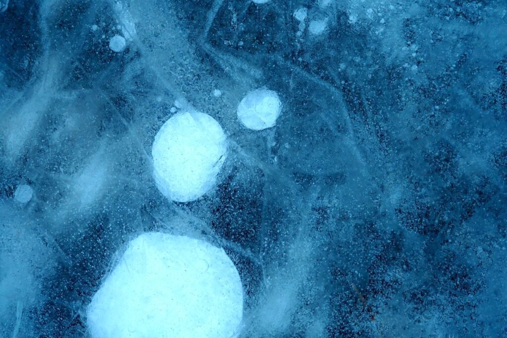 Detailed shot of frozen bubbles trapped in icy surface, showcasing winter's chill.