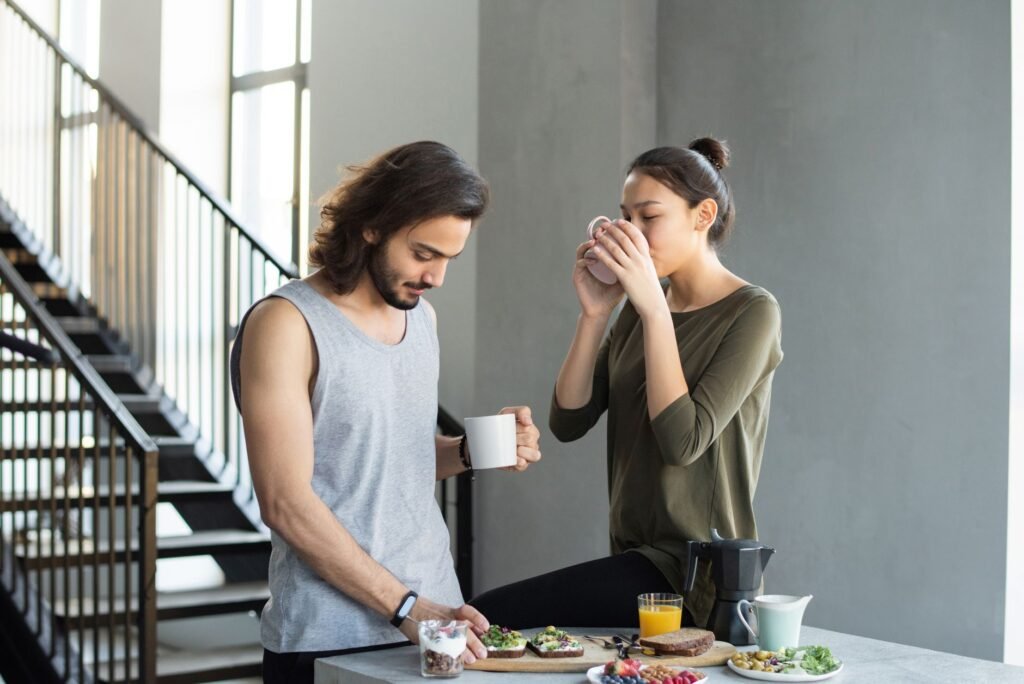 A couple enjoying a cozy breakfast with coffee and juice in their modern home kitchen.