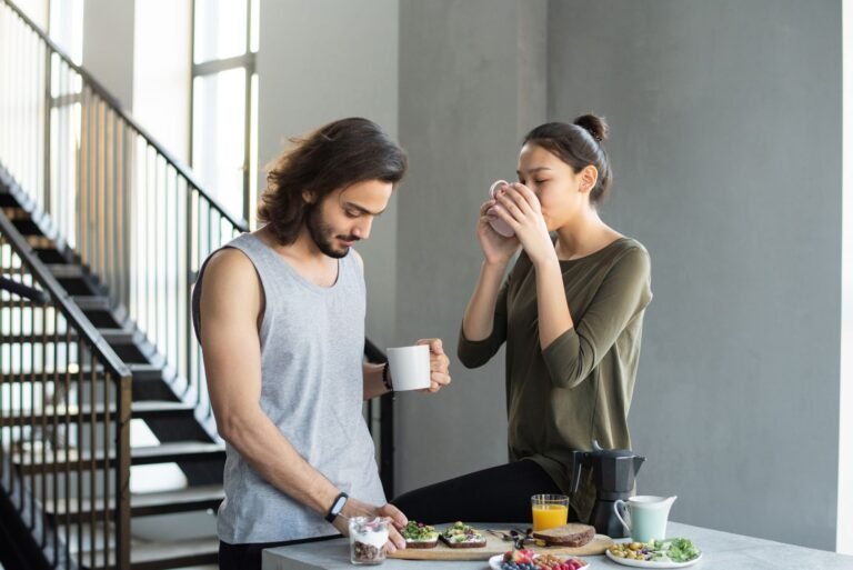A couple enjoying a cozy breakfast with coffee and juice in their modern home kitchen.