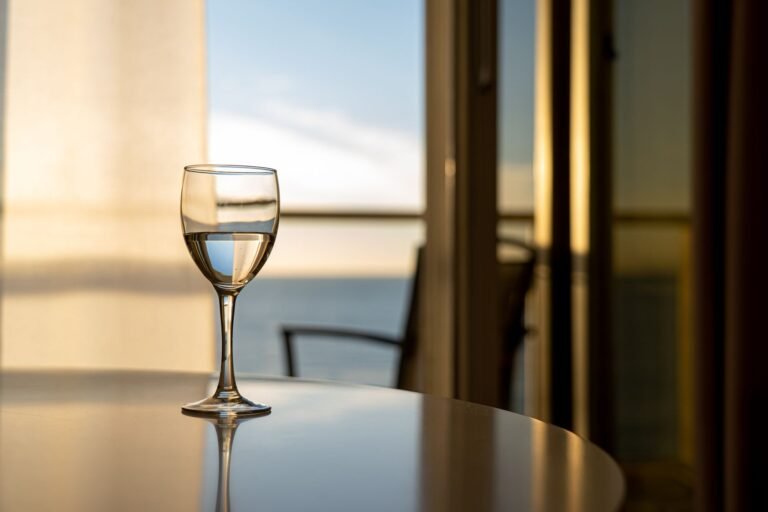 A glass of wine on a table with a stunning ocean view through a window, captured indoors.