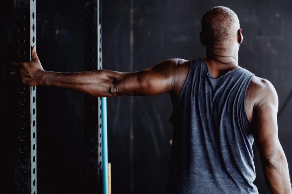 An athletic man stretching his arm in a gym, showcasing strength and flexibility.
