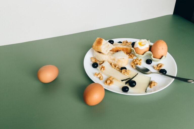 Plate of cheese, boiled eggs, bread, walnuts, and blueberries for a hearty breakfast.