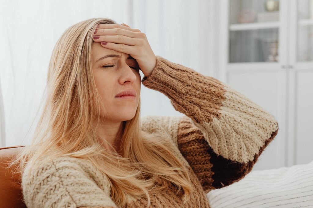Close-up of a woman with a headache, hand on forehead, in a comfortable setting.