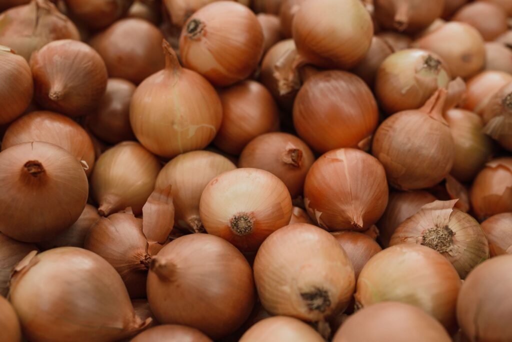 Fresh organic brown onions piled together showcasing natural texture in a close-up shot.