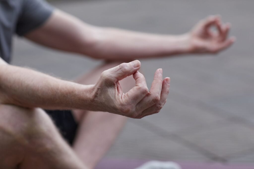 Close-up of hands in a meditation pose outdoors, symbolizing peace and mindfulness.