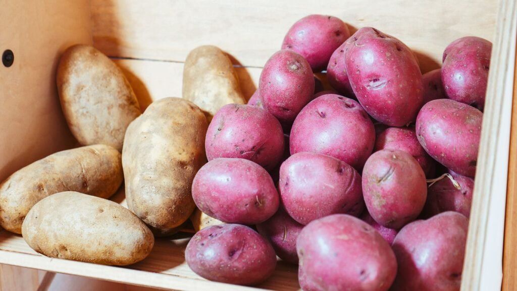 Close-up of fresh red and brown potatoes stored in a wooden crate.