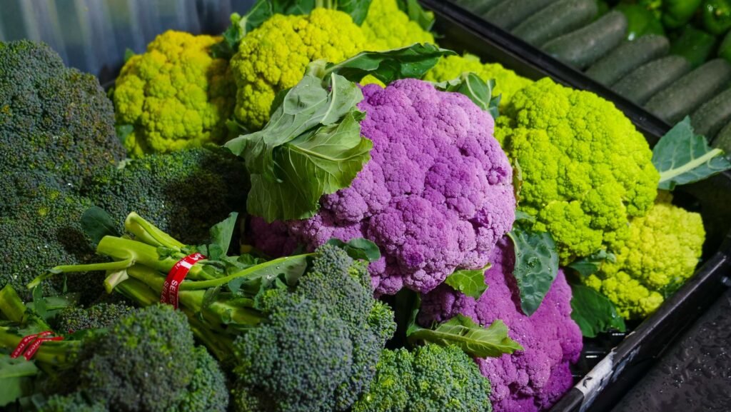 Colorful assortment of fresh broccoli and purple cauliflower at a market. Perfect for healthy food concepts.