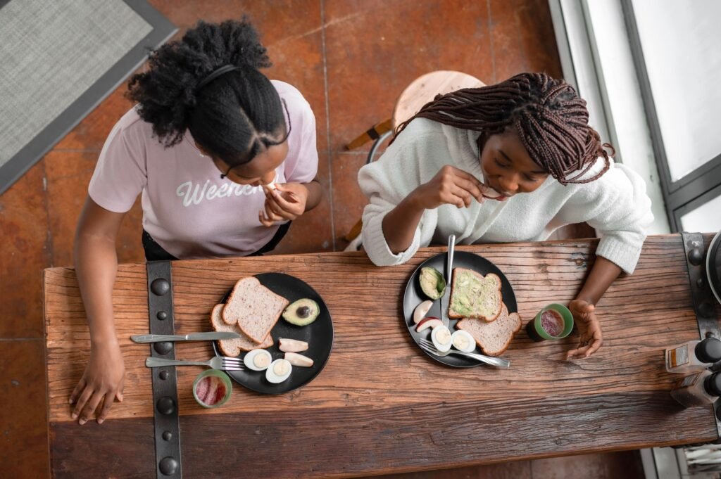 Two women eating a healthy breakfast with toast, avocado, and fruit.