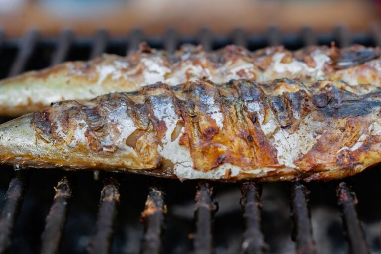 Close-up of grilled fish sizzling on a barbecue grill, perfect for summer dining.