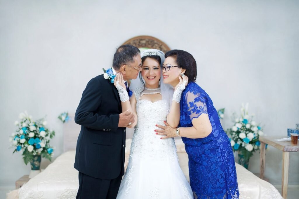 Bride with parents sharing a joyful and elegant wedding moment indoors.