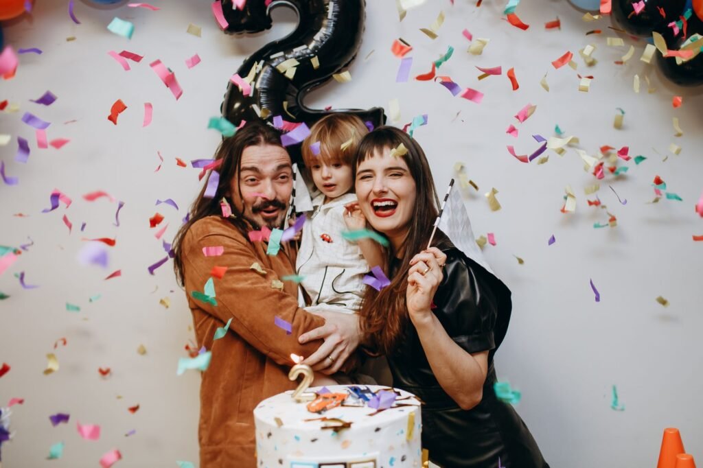 Family celebrating a birthday indoors with confetti and a cake, creating joyful memories.