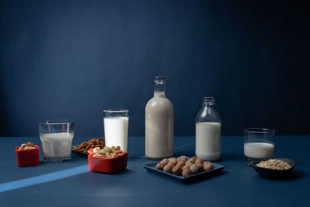 Variety of nut milks and raw nuts arranged on a table against a dark background.
