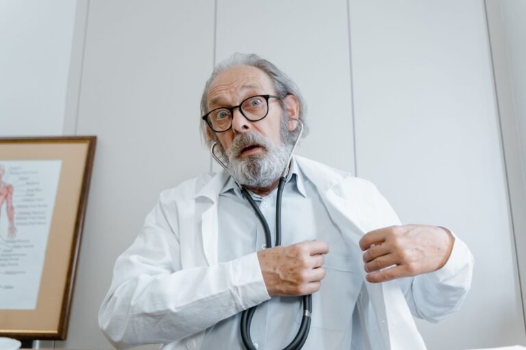 Surprised elderly doctor wearing lab coat and stethoscope indoors.