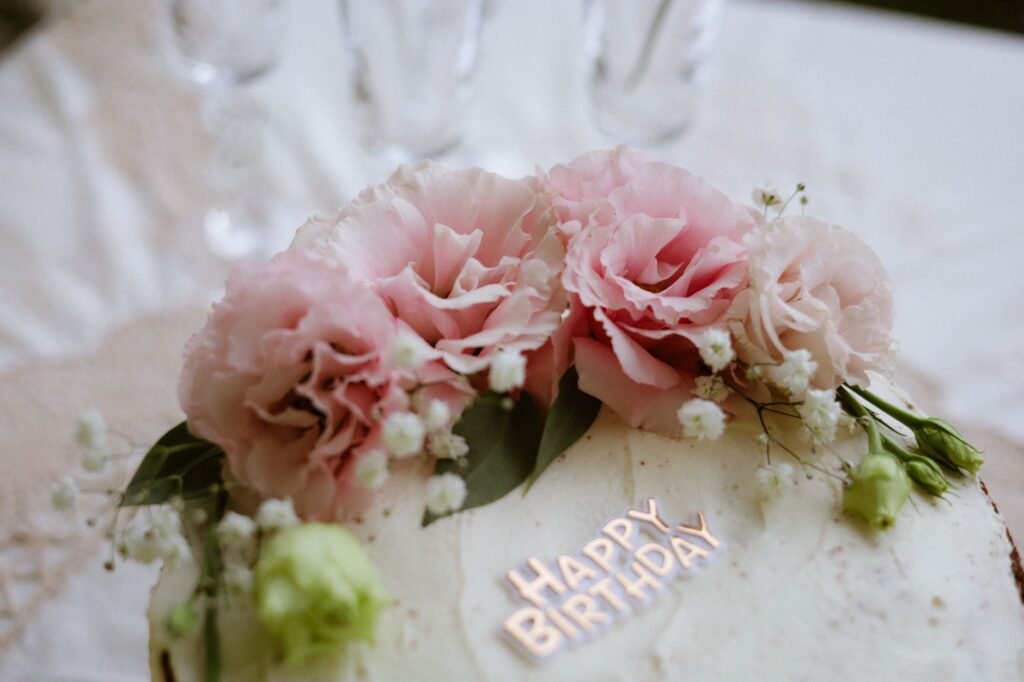 Beautiful birthday cake adorned with lush pink flowers and 'Happy Birthday' text.
